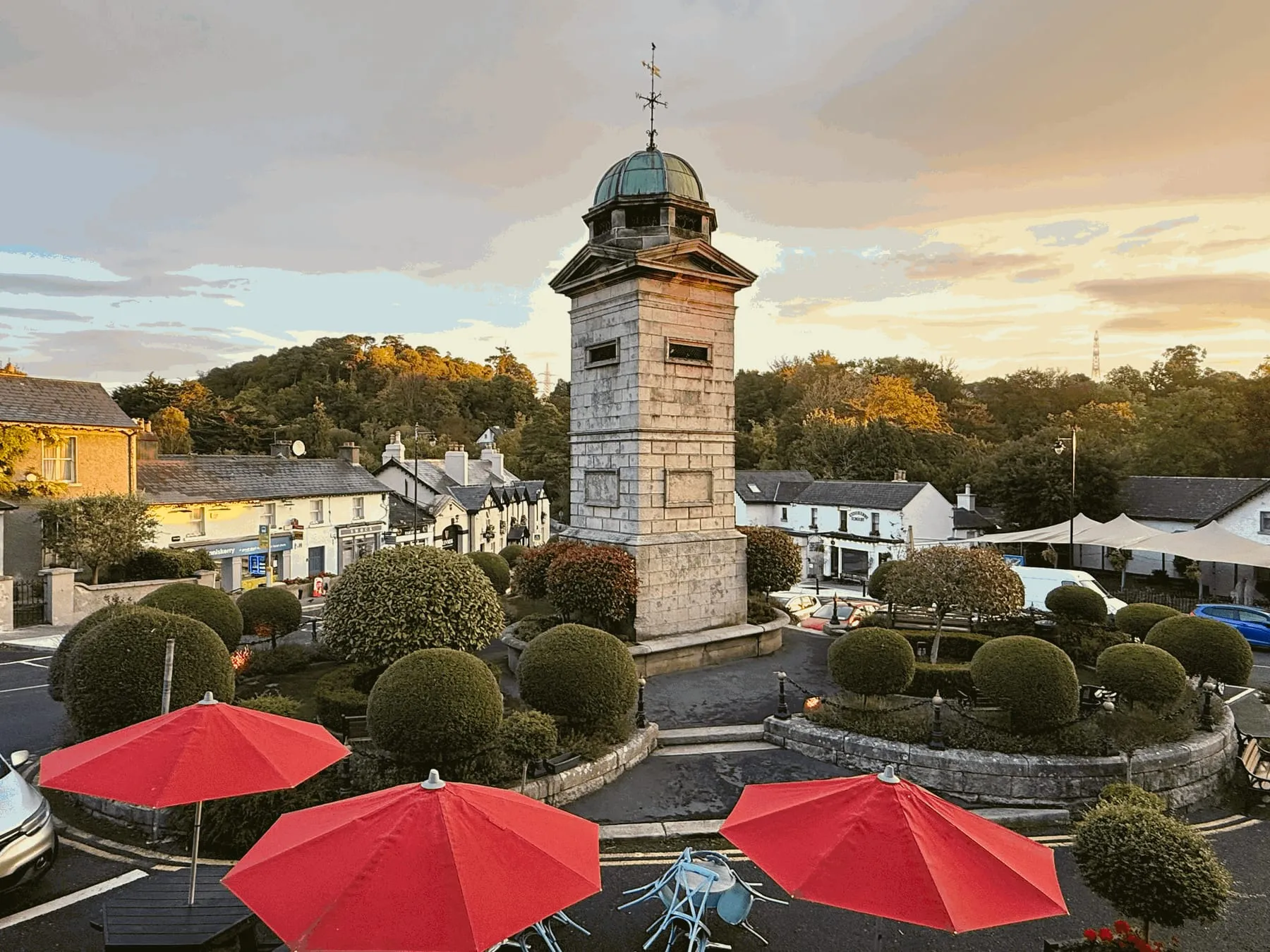 The clock tower on The Square, Enniskerry, seen over the café umbrellas at sunset
