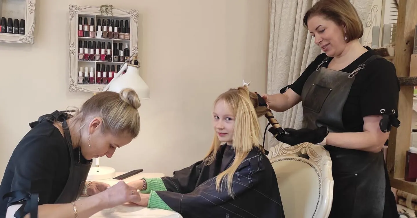 Edita styling hair while Judy works on nails in the salon